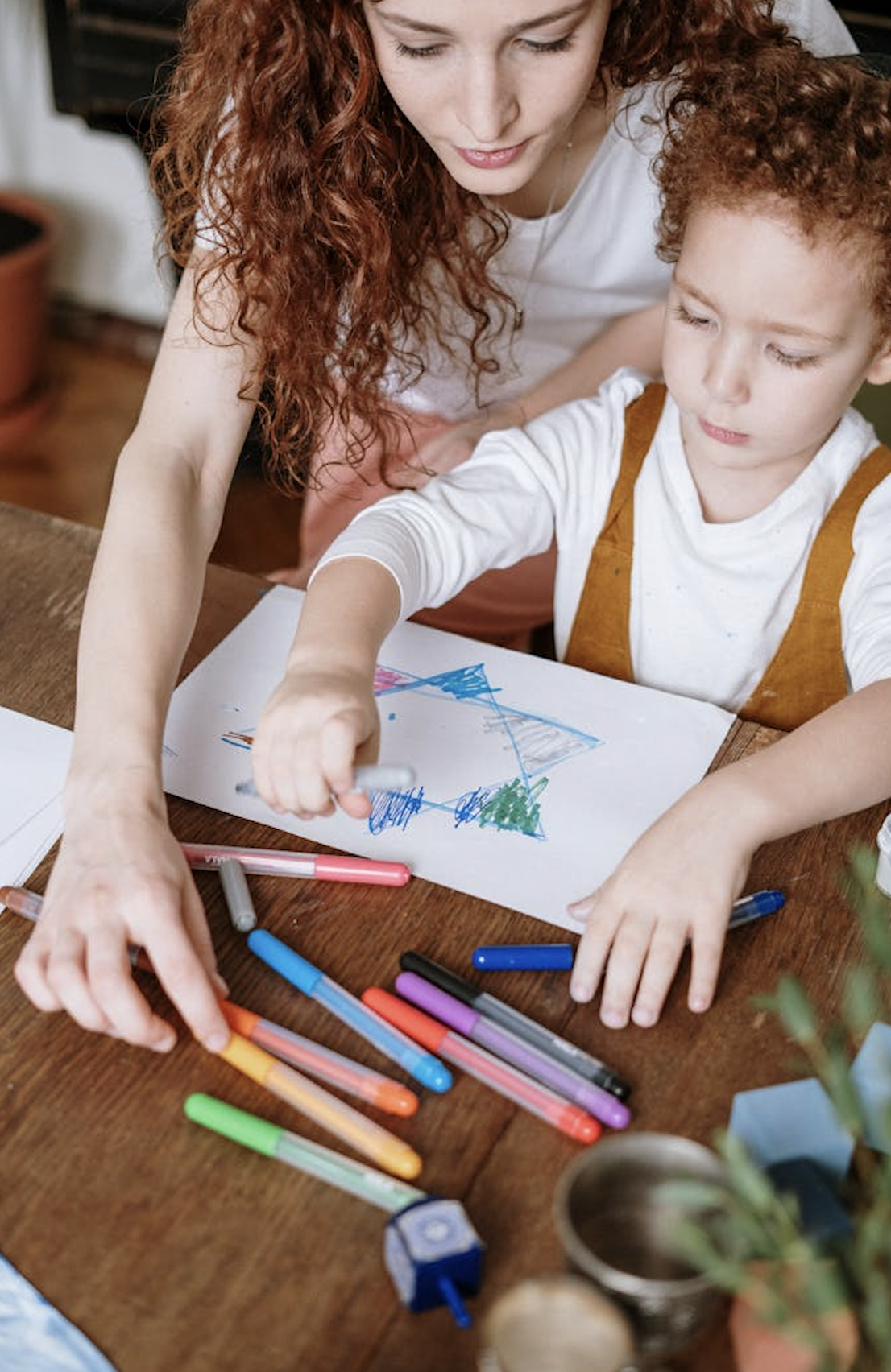 kidzee teacher teaching a student how to draw a drawing.